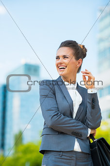 Smiling business woman with briefcase in office district looking