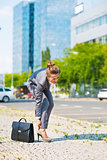 Business woman with briefcase in office district having pain in 