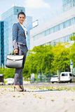 Full length portrait of happy business woman with briefcase in o