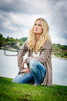 Blond woman kneeling at lake