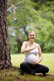 pregnant woman belly yoga meditating tree park
