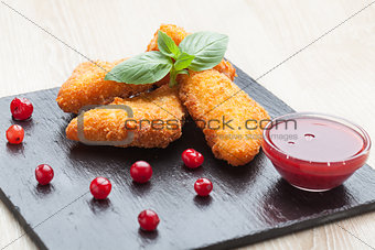 Fried cheese sticks served with cranberries, sauce on black ston