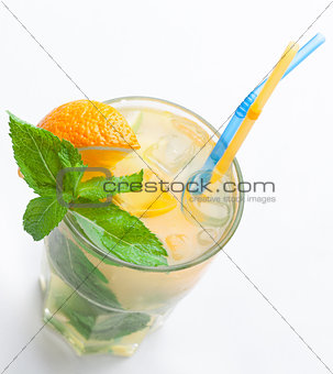 Glass of fresh lemonade with orange, ice cubes, mint, straws