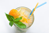 Glass of fresh lemonade with orange, ice cubes, mint, straws