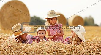 young family on haystacks in cowboy hats