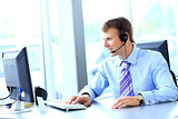 Happy young man working at callcenter, using headset