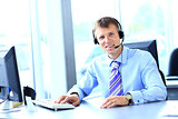 Happy young man working at callcenter, using headset
