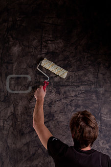 young man painting a black wall