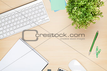 Office table with notepad, computer and flower