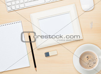 Photo frame on office table with notepad, computer and coffee cu