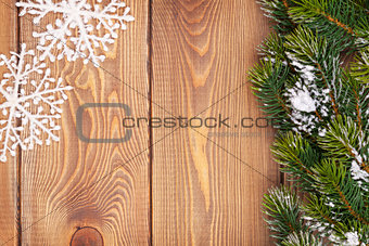 Christmas fir tree with snow and snowflake decor on rustic woode