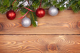 Christmas fir tree with snow and baubles on rustic wooden board