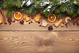 Christmas wooden background with snow fir tree, spices and ginge