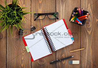 Office table with notepad, colorful pencils, supplies and flower