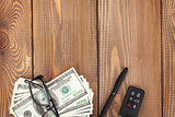 Money, glasses and car key on wooden table
