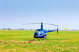Helicopter on a green grass field preparing to take off