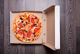 Italian pizza with ham, tomatoes, and olives in box 