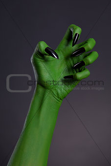 Green witch hand with sharp black nails, real body-art 