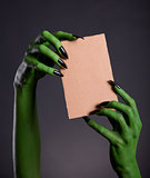 Green monster hands holding empty piece of cardboard 