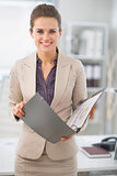 Portrait of happy business woman with documents in office