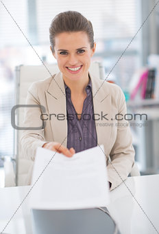 Portrait of happy business woman giving document