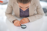Business woman exploring document with magnifying lens