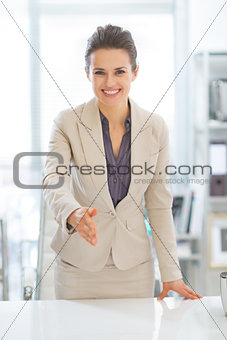 Portrait of happy business woman stretching hand for handshake i