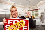Young Woman Holding Sold Sign and Keys Inside New Kitchen