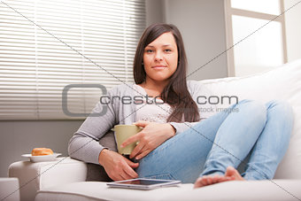 relaxed woman having breakfast in living room