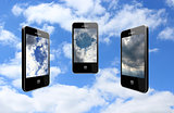 three modern mobile phones on the cloudy sky