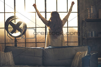 Young woman looking in window in loft apartment and rejoicing. r