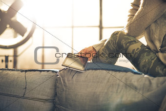 Closeup on young woman sitting with tablet pc in loft apartment
