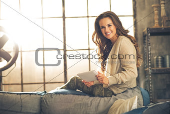 Portrait of happy young woman using tablet pc in loft apartment