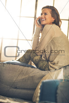 Happy young woman talking cell phone in loft apartment