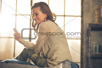 Young woman writing sms in loft apartment