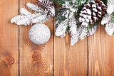 Christmas fir tree with snow and bauble on rustic wooden board