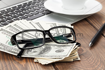 Office table with pc, coffee cup and glasses over money cash