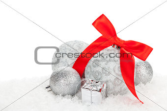 Christmas baubles and red ribbon over snow