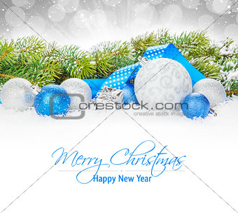 Christmas baubles and blue ribbon with snow fir tree