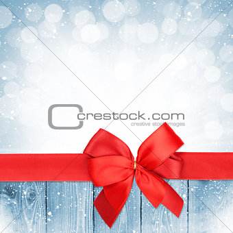 Red ribbon with bow over christmas snow wood background