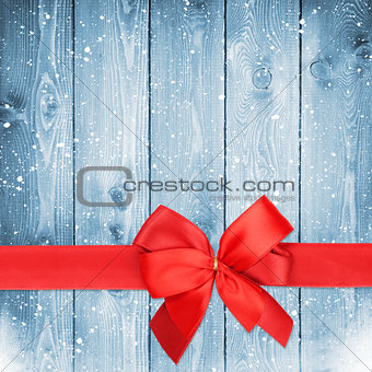 Red ribbon with bow over christmas snow wood background