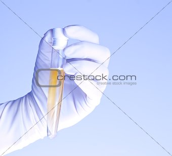close-up of glass tube with yellow fluid in scientist hand during medical test