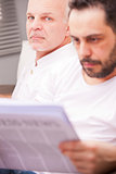 serious man with a friend reading newspaper