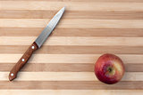 Knife and apple on wooden table board