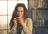 Portrait of smiling young woman with cup of coffee in loft apart
