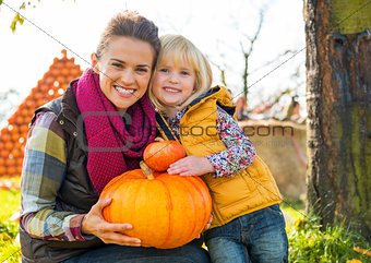 Portrait of happy mother and child holding pumpkin