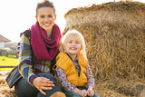 Portrait of happy mother and child sitting on haystack