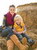 Portrait of happy mother and child sitting on haystack
