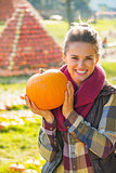 Portrait of smiling young woman showing pumpkin