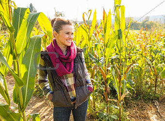 Happy young woman standing in cornfield and looking on copy spac
